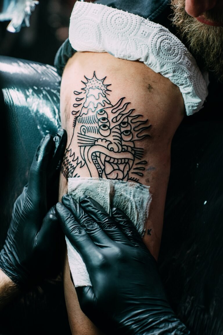 partial view of tattoo artist in gloves working on tattoo on shoulder in salon